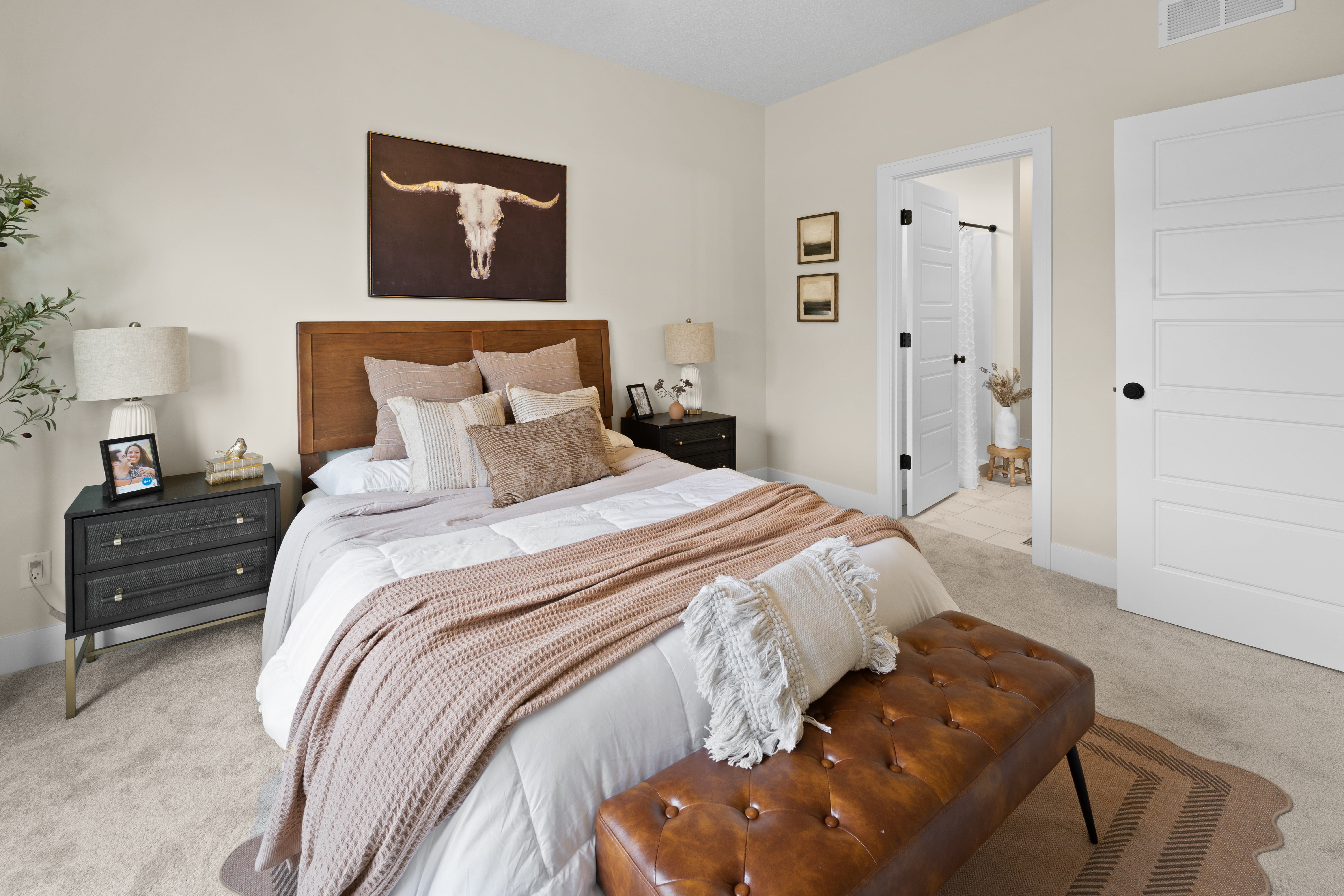 Bedroom with wood headboard, longhorn art, and leather bench